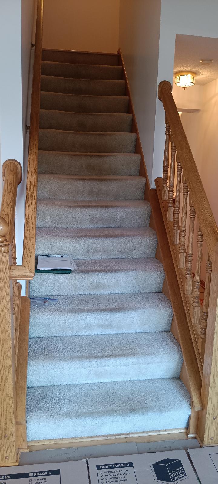 Worn, matted beige carpet on a Woodbury staircase with honey oak handrails before the project began