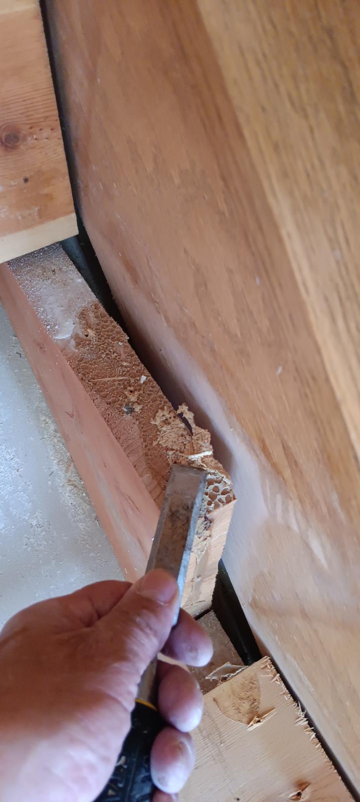 Close-up of a crew member chiseling out damaged, deteriorated wood from the stair structure